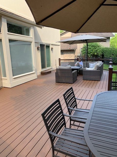 Long composite deck under an umbrella toward a lounge area and the house