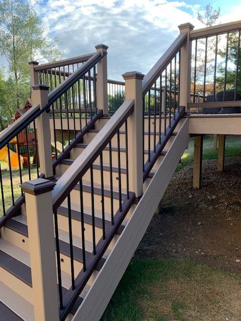 Deck staircase with tan posts and rails, black balusters and cap-lit posts