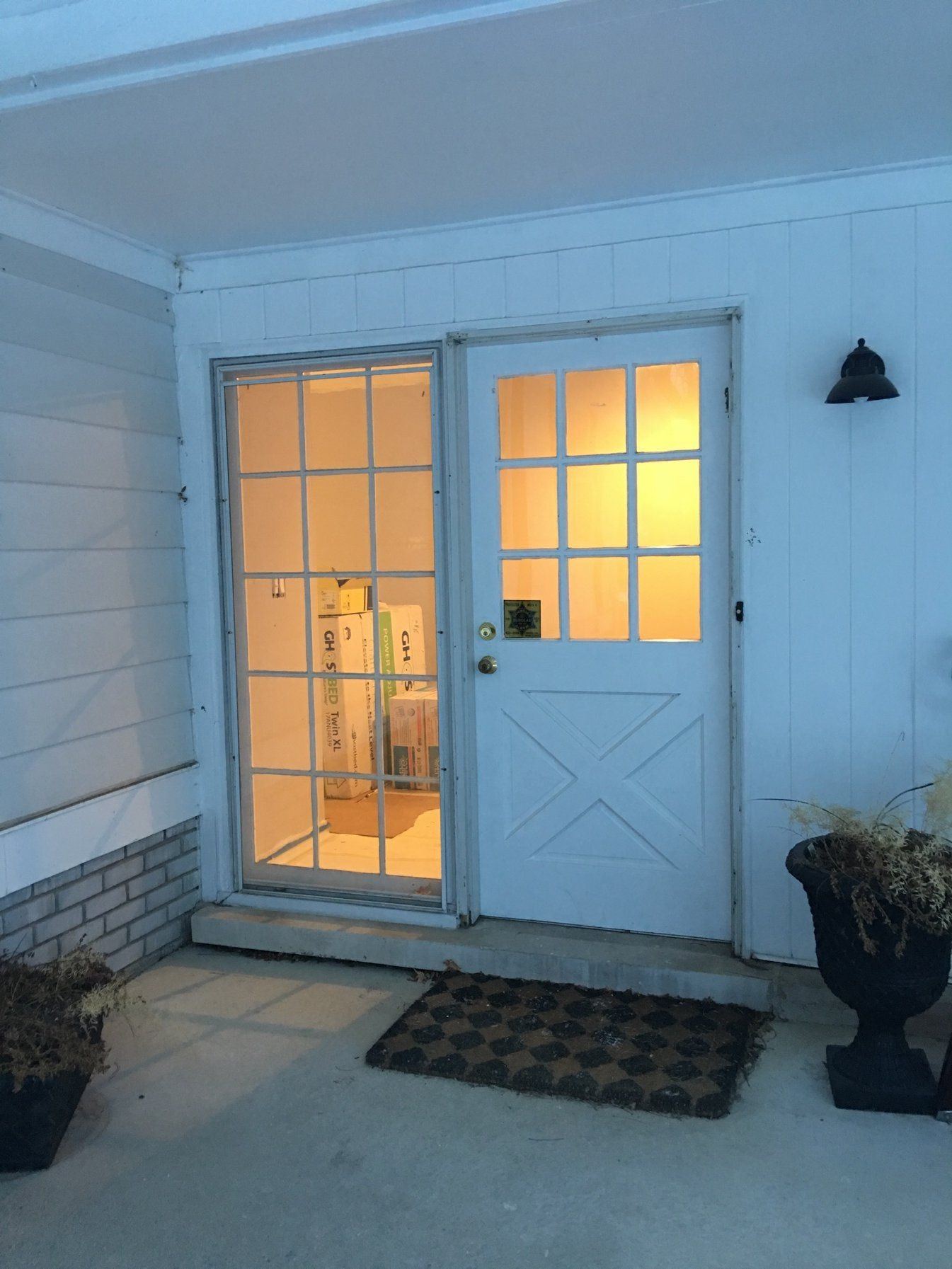 Dated front entry at dusk with a cross-buck half-glass door and a multi-pane sidelight