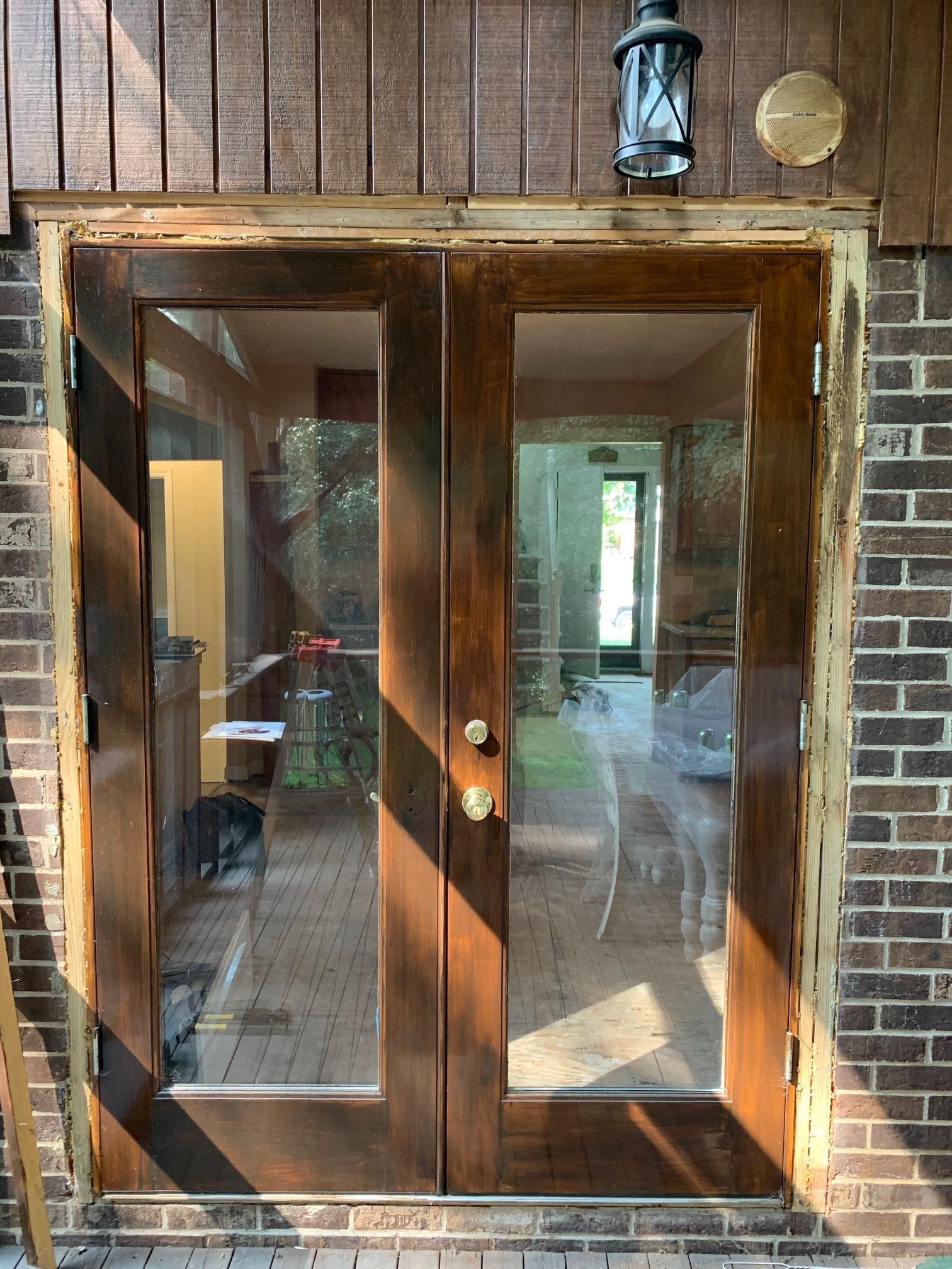 Weathered, water-stained wood French doors under dark wood siding