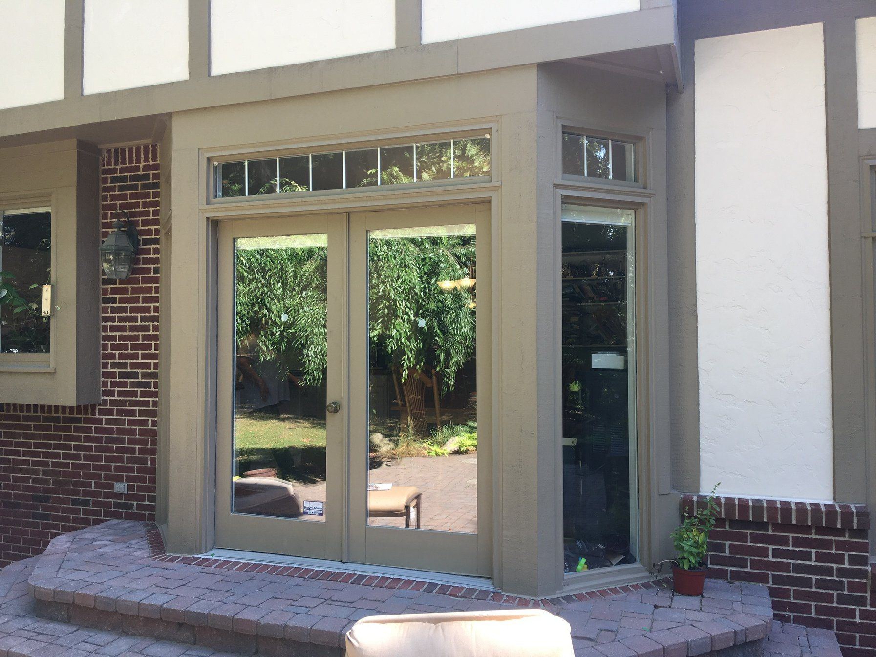 Tudor-style rear bay with tan hinged French patio doors, transom windows and a glass sidelight