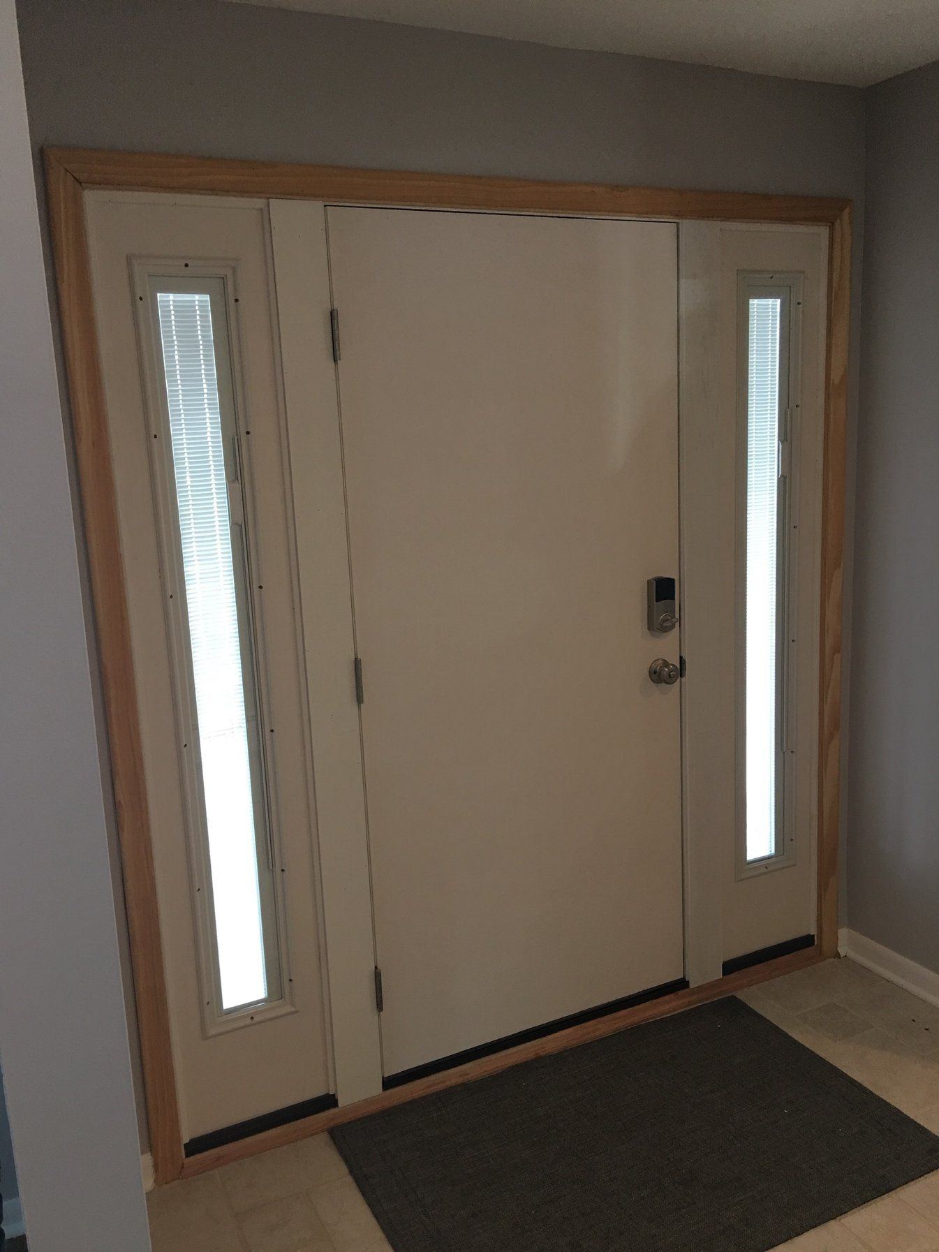 Inside view of a white entry door with two narrow sidelights and a smart lock