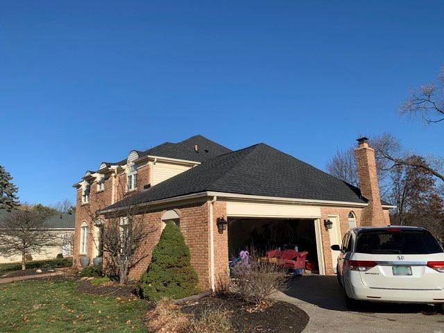 New charcoal shingles over an attached brick garage and chimney