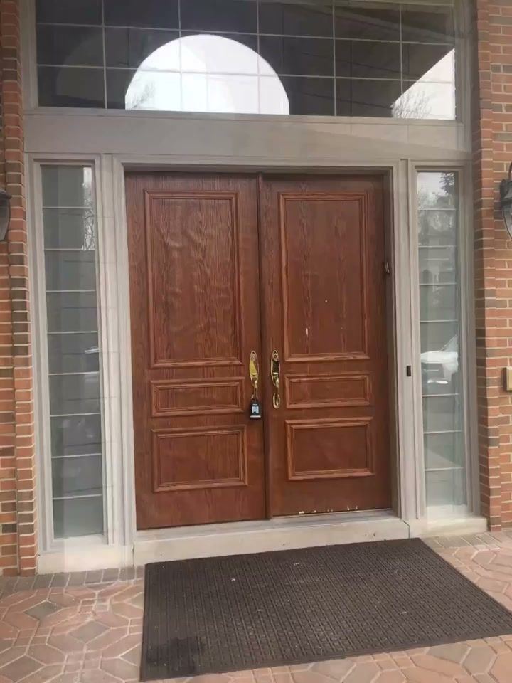 Wood-grain double entry doors with clear sidelights under a half-round transom on a brick facade