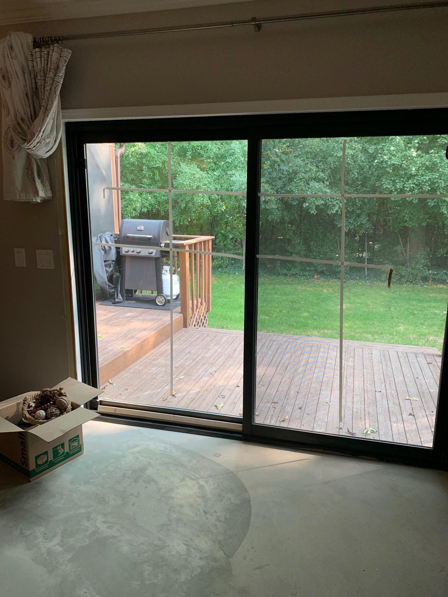 New black sliding patio door seen from inside a room under renovation, opening onto a wood deck