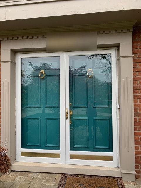 Close view of white full-view double storm doors over teal front doors