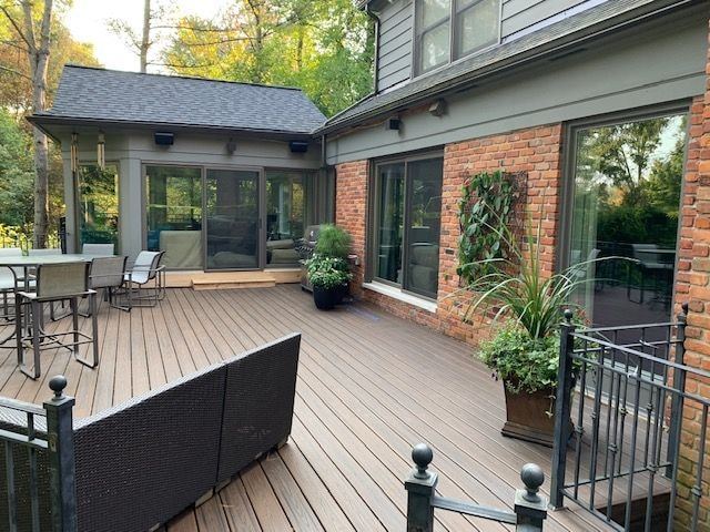 Composite deck looking toward a sunroom and a brick wall with a vertical planter